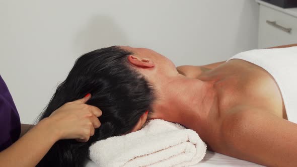 Attractive Mature Woman Relaxing While Receiving Head Massage