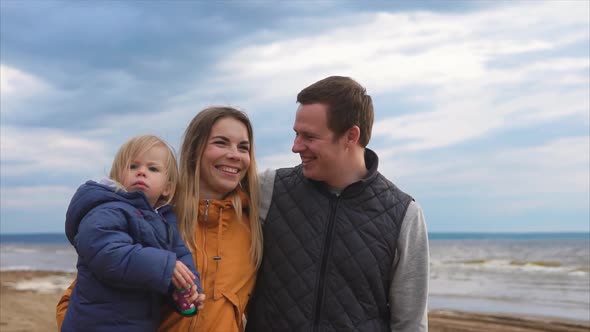 A Young Family with a Small Child Walking Along the Beach on a Cold Day