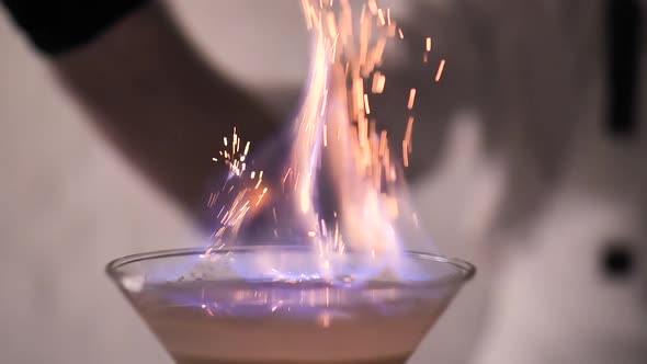 Flames in Cocktail Glass in Slow Motion, Burning Cinnamon in Alcohol Drink, Barman Makes Drink. 