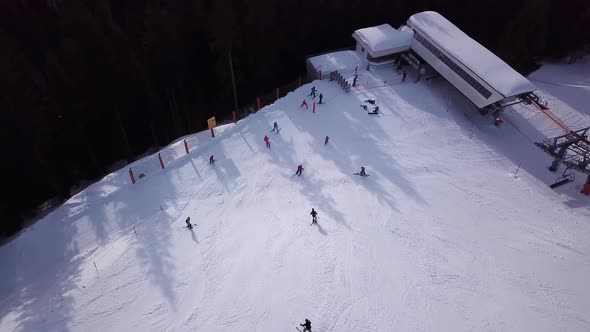 Aerial view of ski resort with people snowboarding down the hill. Stock footage. Flying over the ski