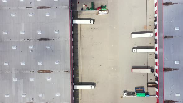 Buildings of logistics center, warehouses near the highway, truck parking process, view from height,
