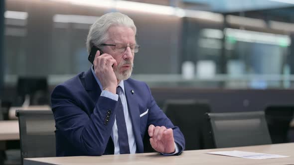 Old Businessman with Laptop Talking on Phone