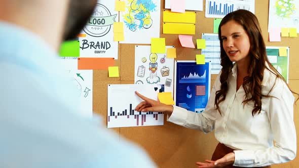 Business colleagues discussing over bulletin board