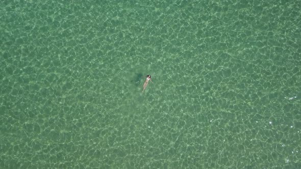 A brown haired woman splashes and swims in the clear waters off Paros island in Greece; summer vacat