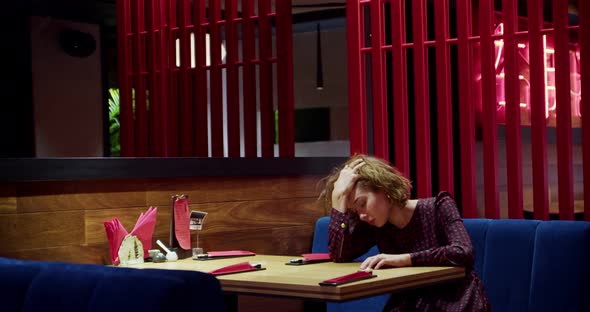 A Young Woman Expresses Disappointment and Fatigue From Waiting Sitting at a Table in an Empty Asian