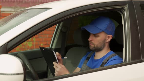 Man Writes Data About Car Details Sitting on Driver Seat