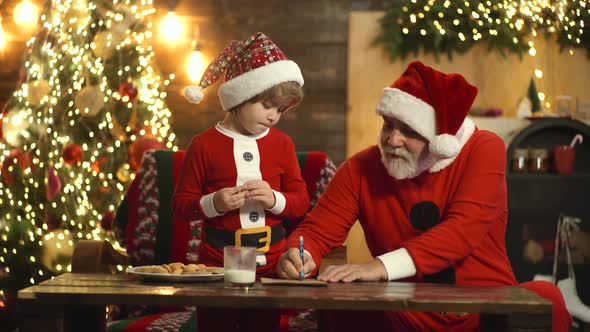 Portrait of Old Parent and Child Writing Letter To Santa Claus. Christmas Helper Reading Wish List