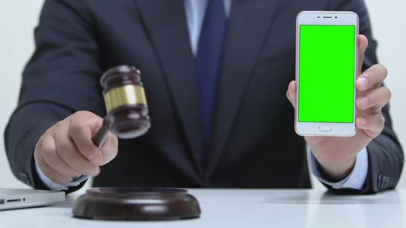 Male Holding Smartphone With Green Screen, Hitting Gavel on Block, Cybercrime