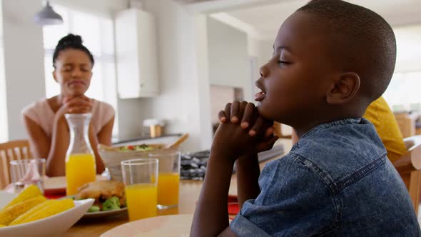 Side view of black family praying together before meal on dining table in a comfortable home 4k