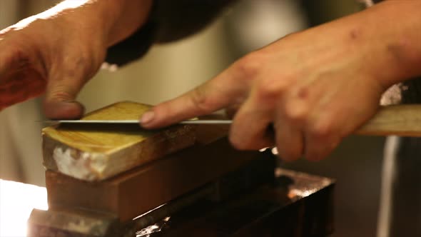 Bladesmith sharpening knife on grindstone