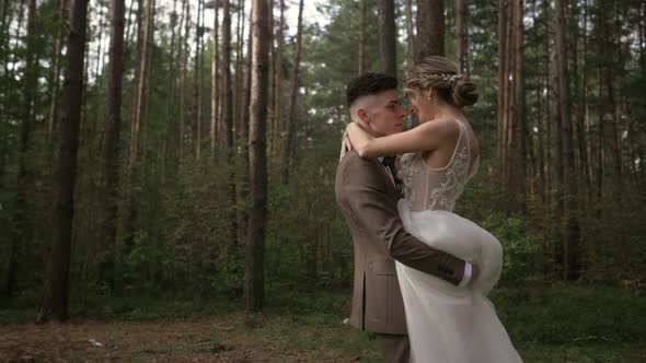 Slow Motion As the Wedding Couple Whirls in the Woods. Beautiful Young Wedding Couple