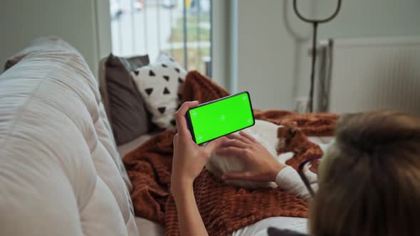 Woman Lying on Sofa and Watch Online Video on Smartphone with Chroma Key