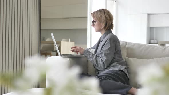 Concentrated Short Haired Blonde Young Woman Types on Laptop