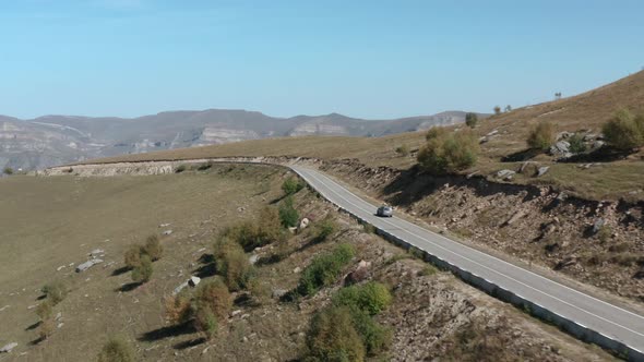 Contemporary Tourist Vehicle Drives Travel Along Empty Curved Asphalt Serpentine Road Among Brown