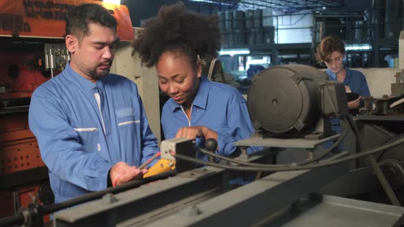 Two professional engineers inspect machines' electric systems at the factory.