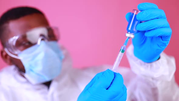 African American Man Scientist in PPE Suite Uniform Showing Medicine Liquid Vaccine Vial Bottle