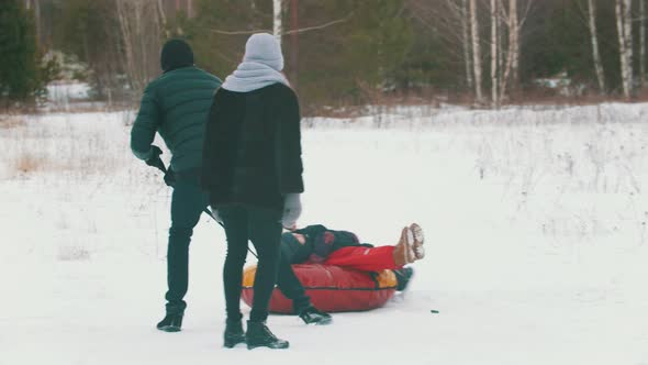 A Man Rolls His Child on the Inflatable Sled