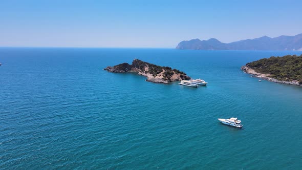 Drone shooting endless sea with pleasure boats small islands and mountain ranges.
