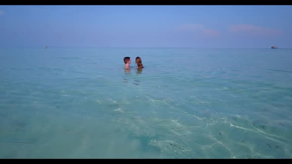 Man and woman posing on tropical seashore beach journey by aqua blue sea with white sandy background