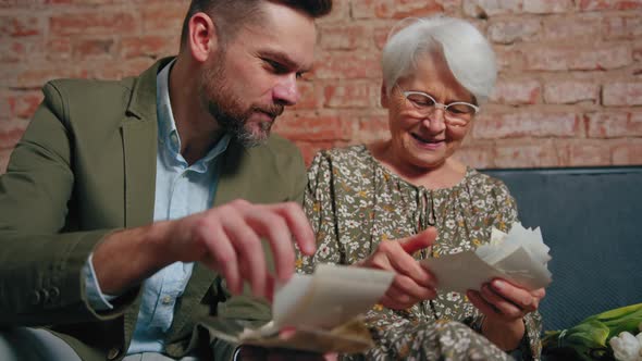 European Businessman in His 30s and His Retired Vivacious Mother Cheerfully Looking at Old