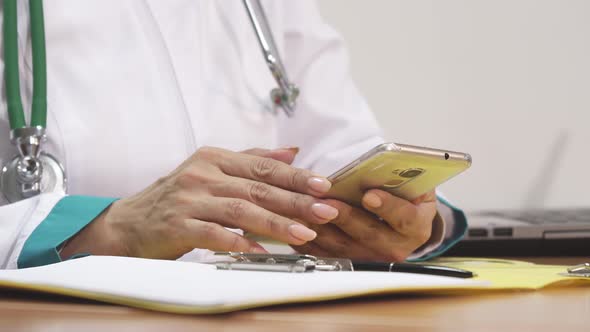 Female Doctor Using Smart Phone Writing Notes