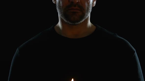 Man From Religious Sect Holding Candle Against Black Background, Spirituality