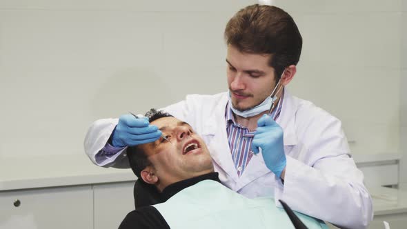 Young Male Dentist Smiling During Dental Checkup of His Patient