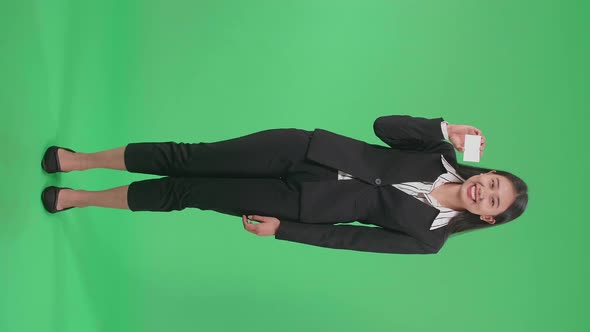 Full Body Of Asian Business Woman With Smile Holding A White Card While Standing On Green Screen