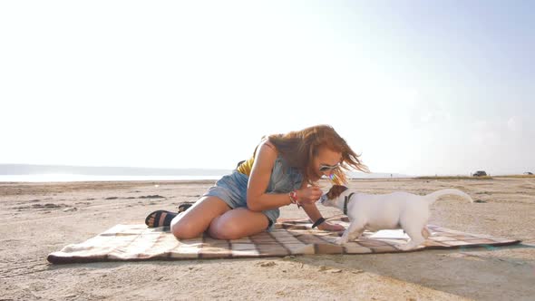 Young Stylish Hipster Playing Dog Puppy Jack Russell on the Beach Slow Motion