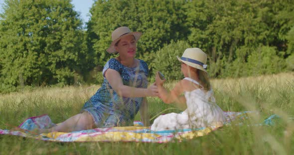 Mother and Daughter Take a Selfie on a Smartphone on the Lawn Park Summer