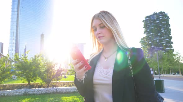 Slow motion shot of businesswoman using red smartphone in park