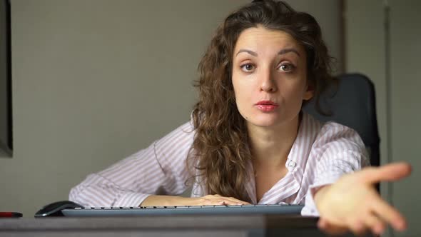 Tired Young Woman with Curly Hair and White Shirt is Working at the Office Using Her Laptop Routine