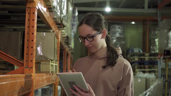 Beautiful Young Woman Worker in Warehouse of Shopping Center