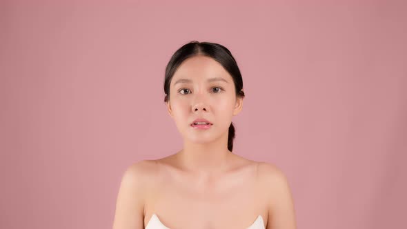 Slow motion Beauty shot of Beautiful Asian girl looking at camera isolated on pink background
