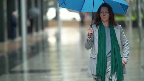 Adult Woman Is Walking Under Rain in City, Holding Umbrella, Wet Street of Downtown at Autumn Day