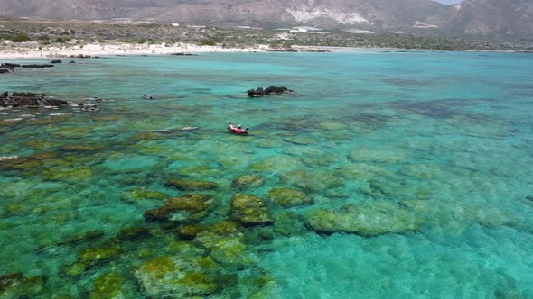 Aerial shot of couple kayaking in turquoise sea during summer day. Travel tropical island holiday co