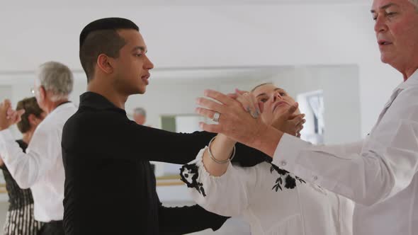 mixed race male dance teacher taking a ballroom dancing class at a dance studio