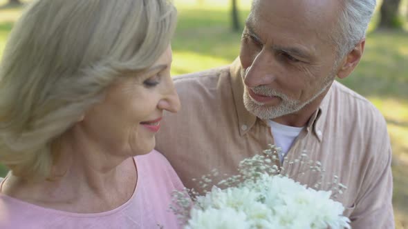 Senior Man Giving Flowers to Beloved Woman Pleasant Surprise Attention Care