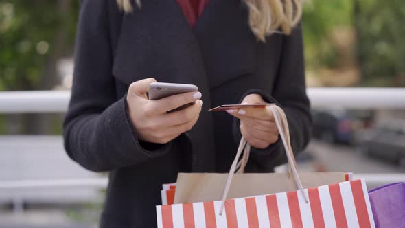 Close Up of Caucasian Woman's Hands Making Payment Online Using Her Mobile Phone and Credit Card