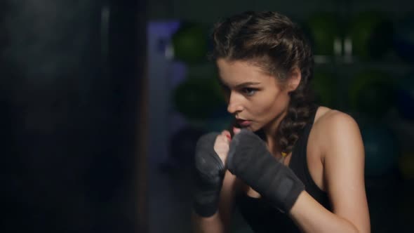 Closeup View of a Young Woman Punching a Boxing Bag with Her Hands Wrapped in Boxing Tapes