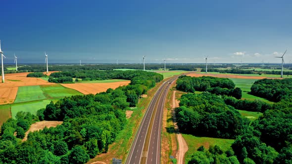 Wind turbines, road and green fields in summer, aerial view