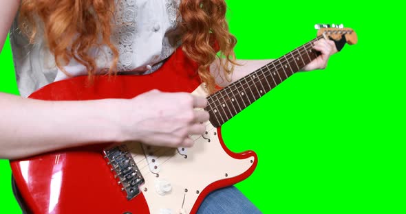 Mid section of female musician playing guitar