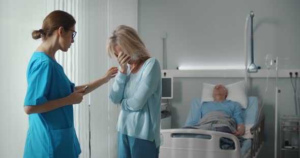 Doctor Telling Bad News To Aged Male Patient Wife in Hospital