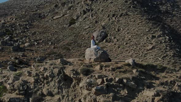 Woman in White Cloth Calm Sitting on the Stone at Top of the Hill in the Middle of the Valley