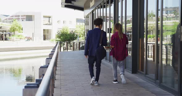 Two diverse male friends walking in the street looking at smartphone