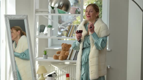 Desperate Hopeless Middle Aged Caucasian Woman Crying Drinking Red Wine Standing at Home Alone
