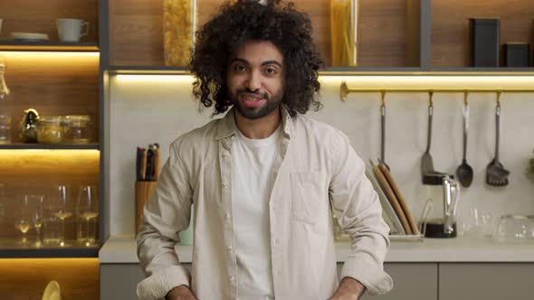 Young Muslim Man Talks Looking in Camera Standing in Kitchen