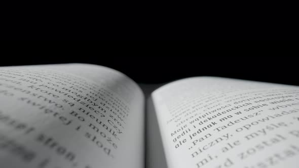 Open Book with White Paper Pages and Text Lying on Black Isolated Studio Background