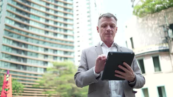 senior businessman working confident on a laptop, business person man working outside office in city