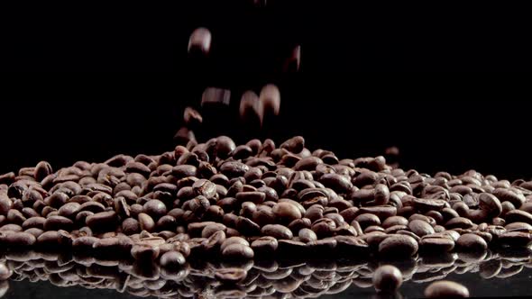 Coffee beans fall on a black glass